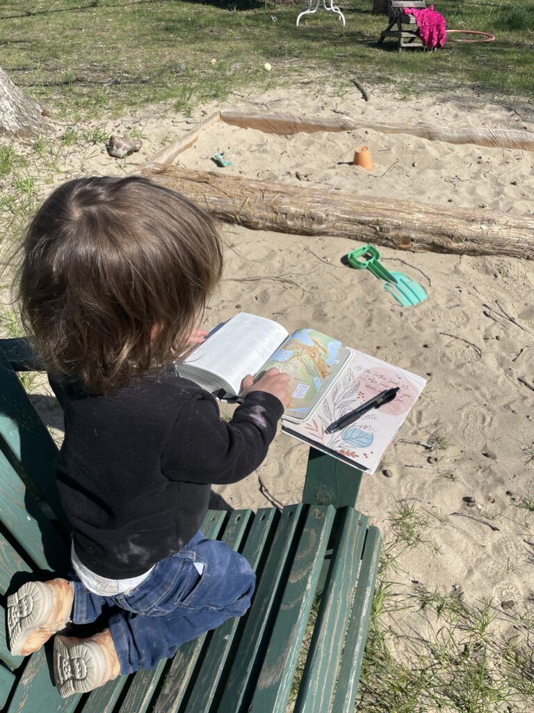 A little girl sits on a green lawn chair, focused on her open Bible with a notebook and pen next to her. Which poses the question, When to do devotions according to the Bible?