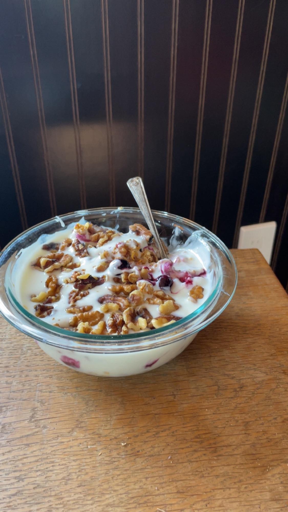 The successful result of the recipe: a glass bowl of thick, gelatin-free yogurt garnished with walnuts and frozen berries.