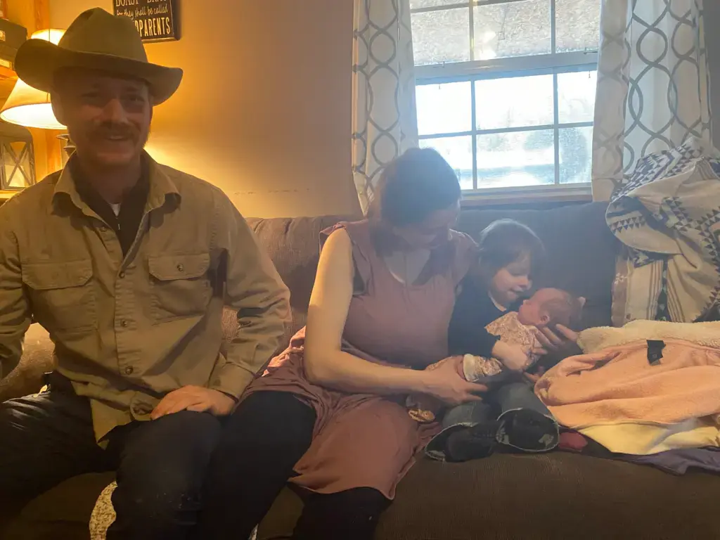 Too Late for the Hospital: My 37-Week Unplanned Home Birth and the Helicopter Ride to the NICU 18 The first family photo of the four of us: two-year-old Timberlynn holds newborn Wrangler on her lap, supported by their mother, Brittney. Papa Carson sits next to them on the couch, smiling.