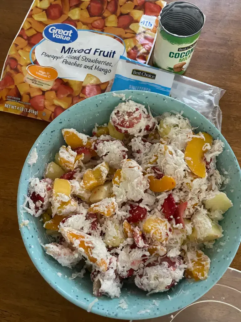 3 ingredient creamy tropical fruit salad, freshly mixed with the empty bags and can sitting beside it.