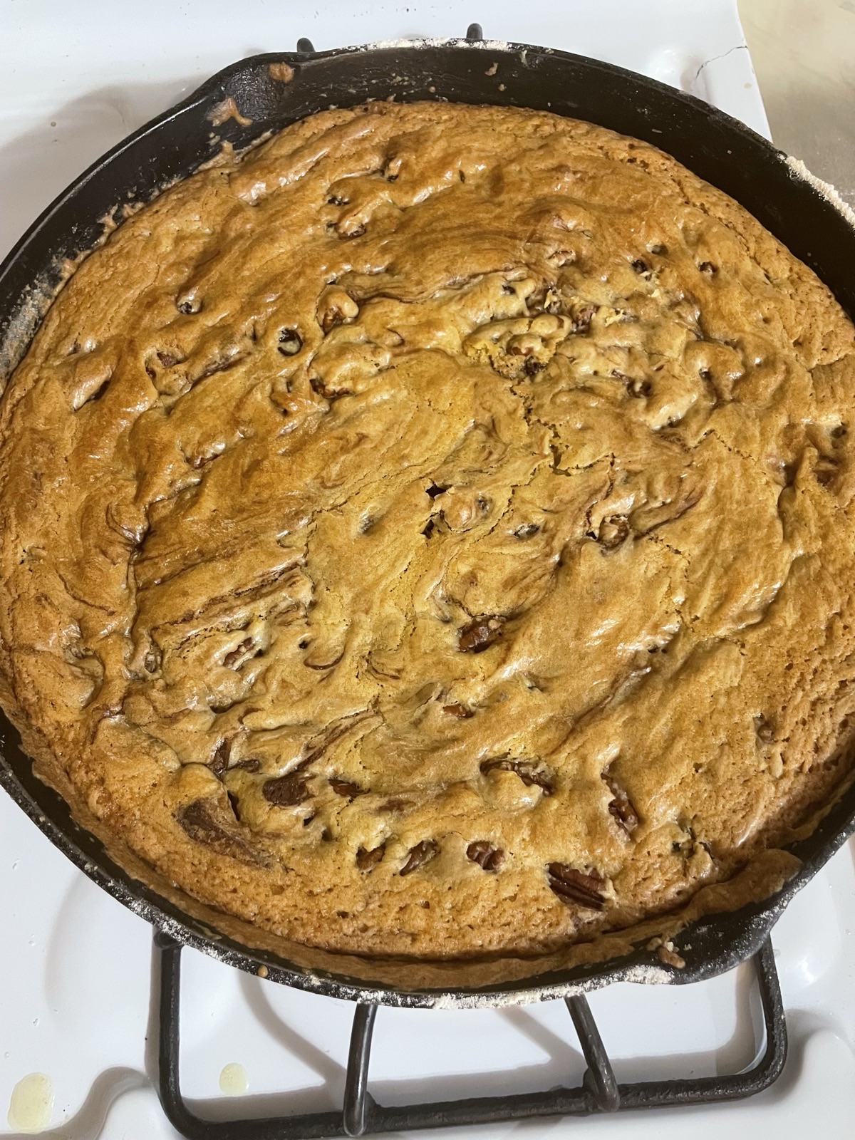 A close-up of a chewy-textured chocolate chip skillet cookie in a cast iron skillet. One of the best no-scale sourdough recipes.